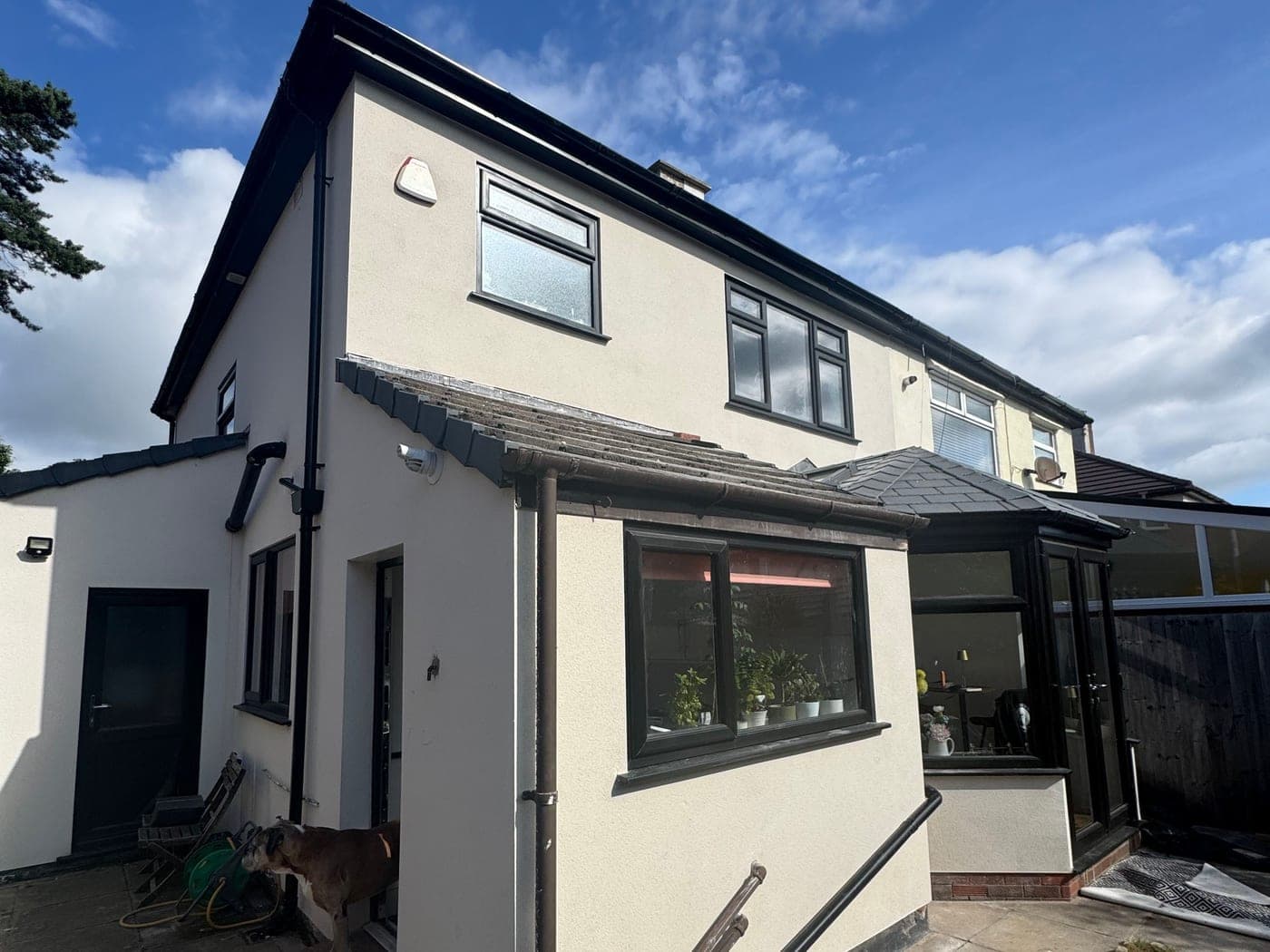 Rear elevation of a semi-detached house finished in cream K Rend, worked around an existing conservatory