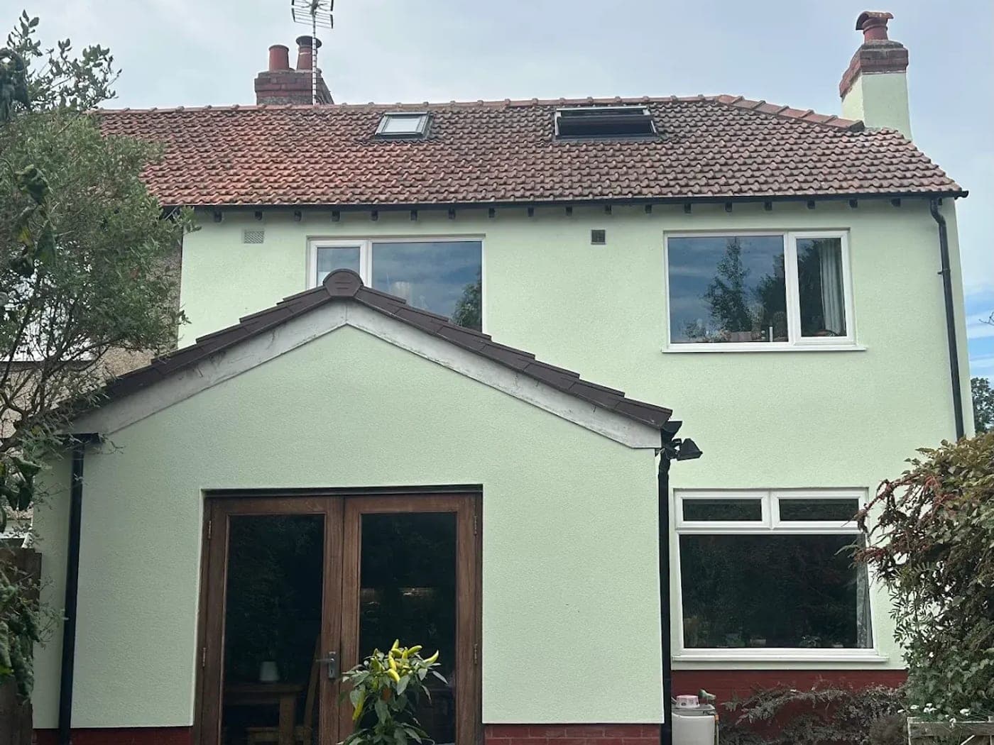 Detached cottage rendered throughout in pale green, with the porch gable and rear elevation finished to match