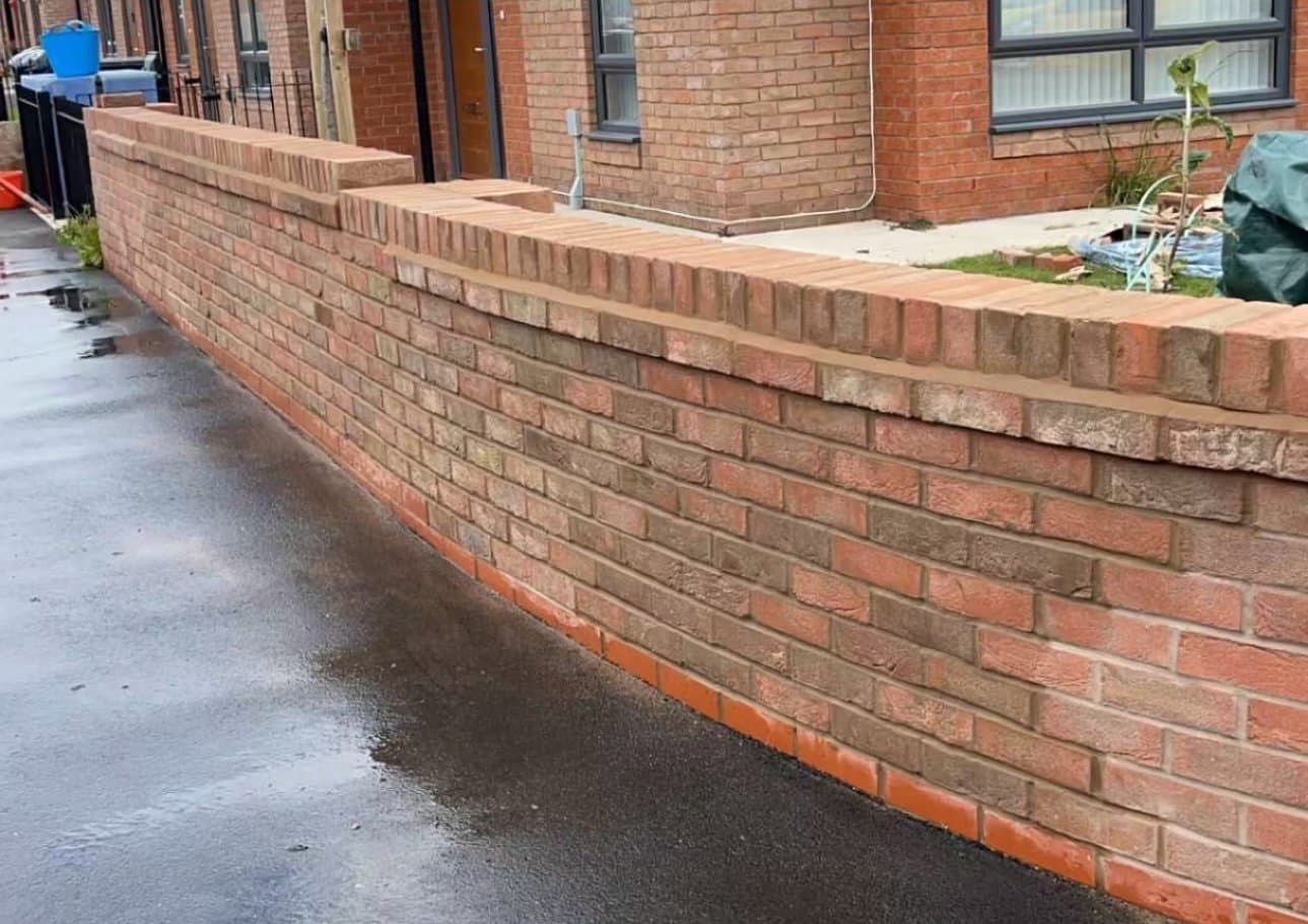 Brick boundary wall with brick-on-edge coping running alongside a driveway