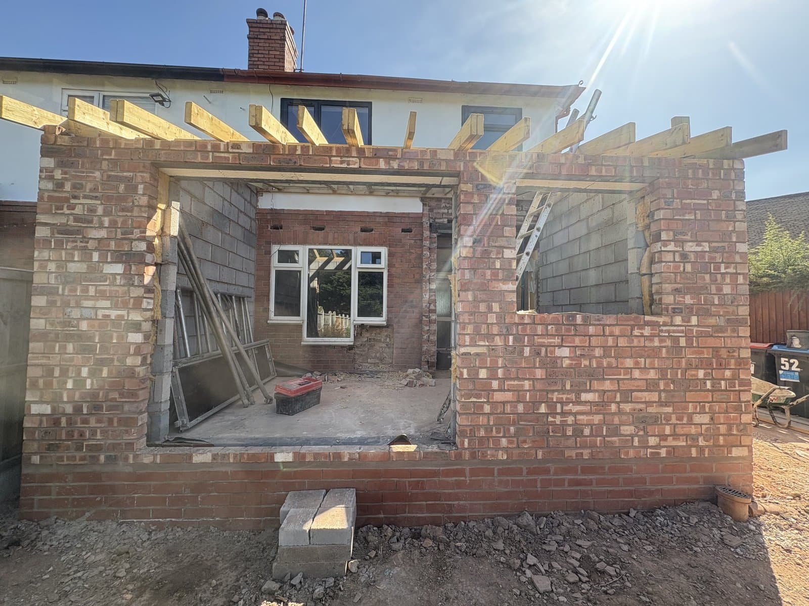 House extension under construction in brick and blockwork, with timber roof trusses in place